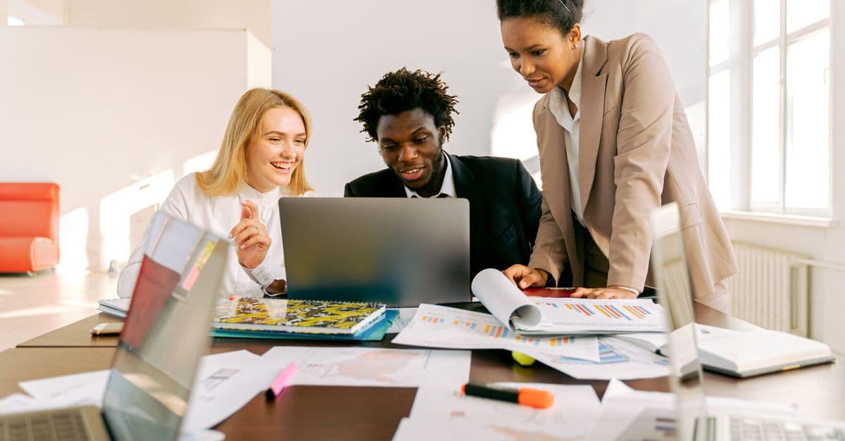 A SaaS team collaborating around a laptop in a bright office.