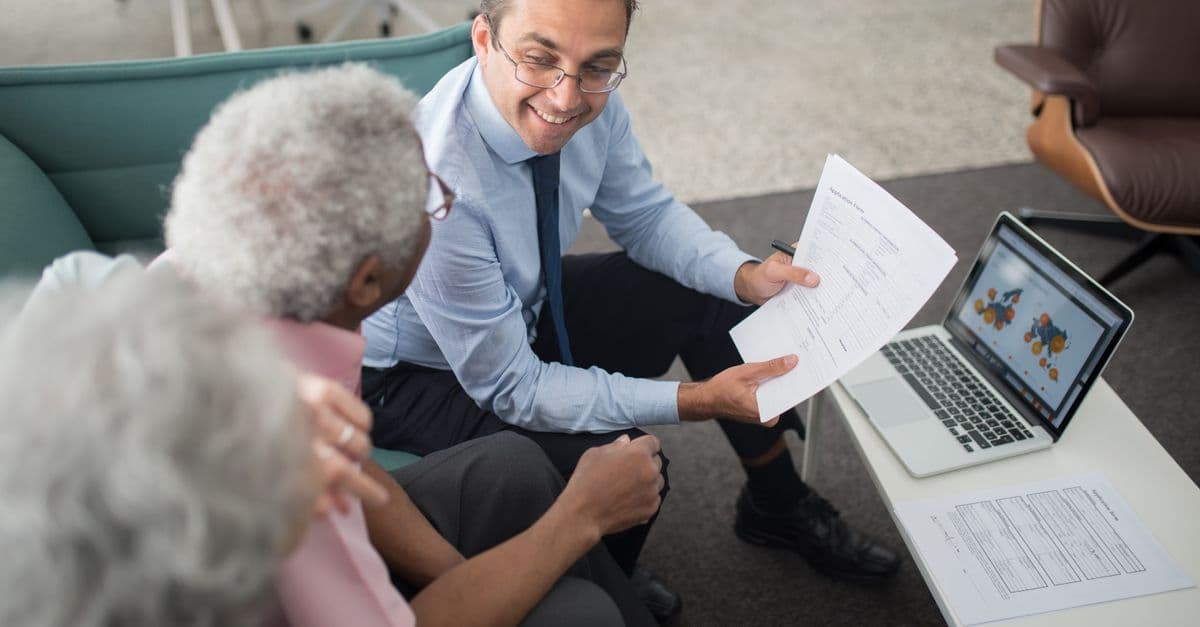 An insurance adviser reviewing policy documents with two clients.