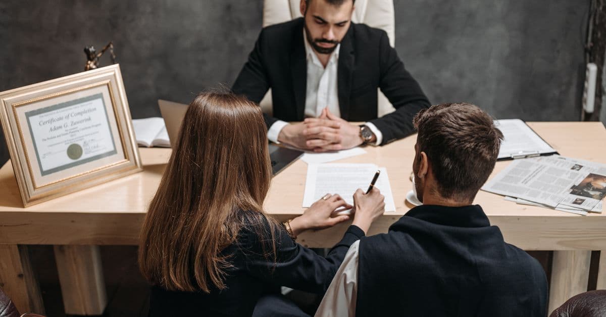 A lawyer consulting with two clients across an office desk.